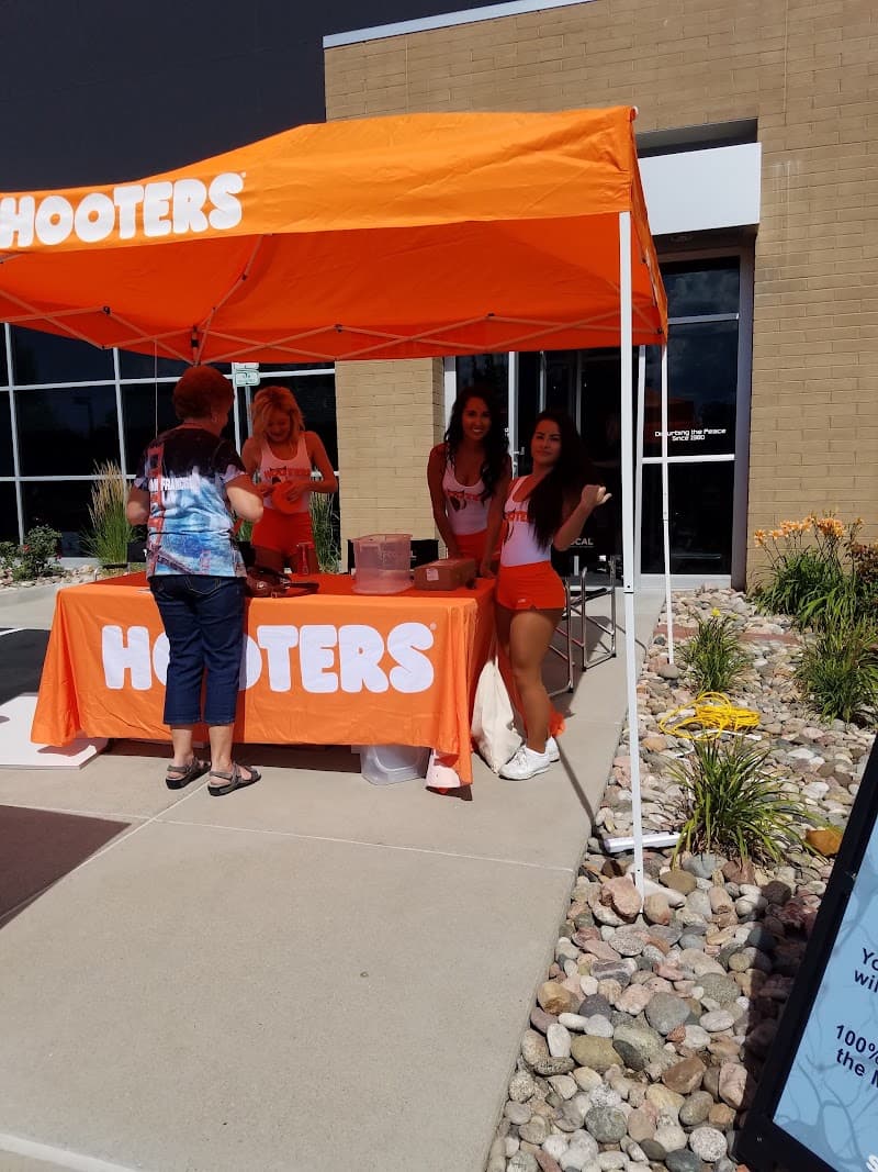 Outdoor orange canopy table with staff and a customer at PDA Road Gear in Littleton, Colorado