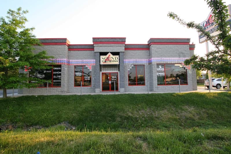 Gray block storefront with red trim and glass entry doors at Sound of Tri-State in Dover, Delaware