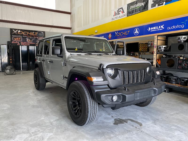 Silver SUV with black wheels parked in shop bay at Xochilt Car Audio in Houston, Texas