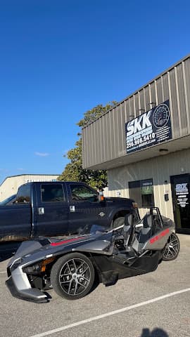 Three-wheel roadster parked beside a pickup truck outside the shop at SKK Accessories & Car Audio in Athens, Alabama