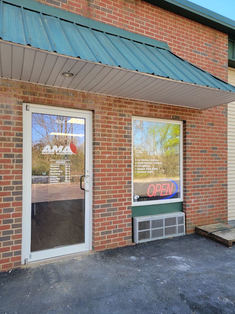 Brick storefront with green awning and an OPEN sign in the window at A.M.A Audio Customs in Gainesville, Georgia
