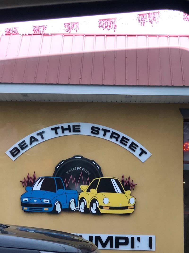 Painted sign of a blue pickup and yellow car on a wall at Thumpin Car Stereo Inc in Hagerstown, Maryland
