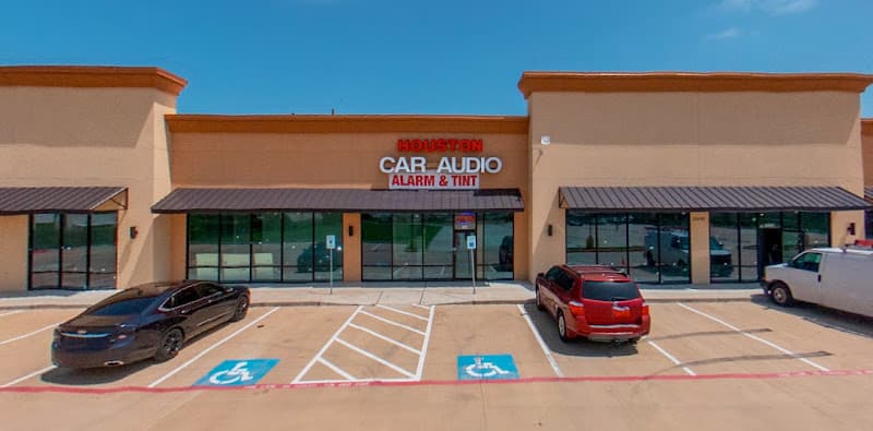 Tan storefront with Houston Car Audio sign and two parked cars at Houston Car Audio in Cypress, Texas