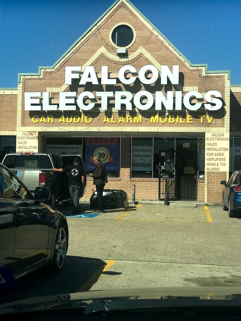 Brick storefront with white sign and two men beside an SUV at Falcon Electronics in Houston, Texas