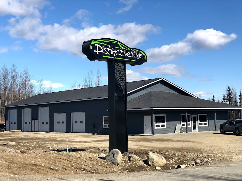 Black pole sign with green car logo beside a shop building at Distinctive Ride Wasilla in Wasilla, Alaska