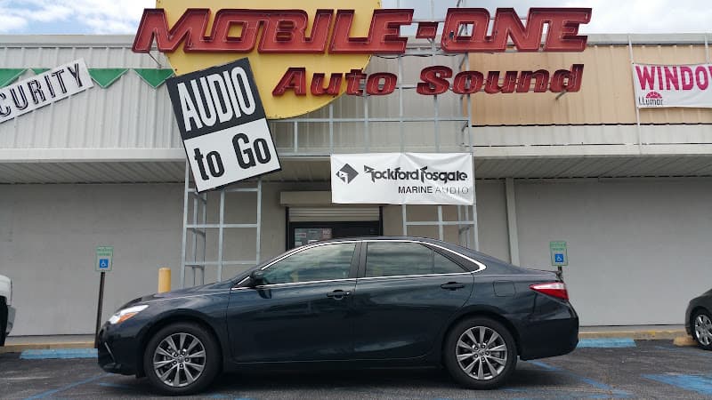 Storefront with a Rockford Fosgate banner and a parked sedan at Mobile One Auto Sound, Inc. in Metairie, Louisiana