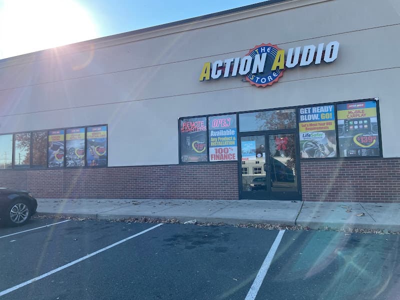 Storefront with lit sign and window banners for remote starters at Action Audio Store LLC in Wethersfield, Connecticut