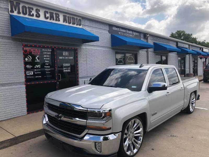 Silver Chevrolet pickup with chrome wheels parked outside shop at MoesKustomz in Wylie, Texas