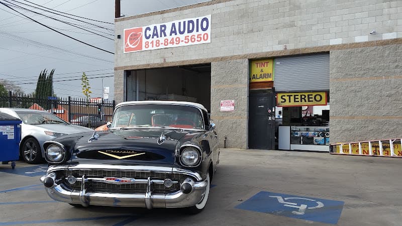 Classic Chevrolet coupe parked outside a block building with CAR AUDIO sign at Audio Planet Inc in Van Nuys, California