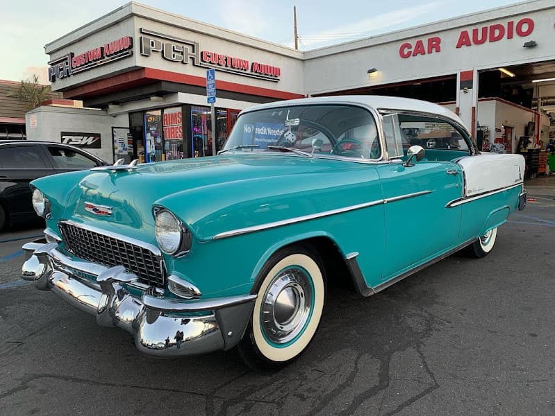 Teal and white classic car parked outside a car audio shop at Onlinecarstereo in Murrieta, California