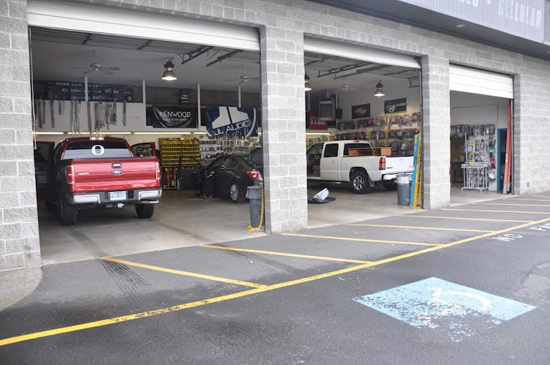 Three open service bays with a red pickup and sedan inside at Progressive Audio Inc. in Medford, Oregon