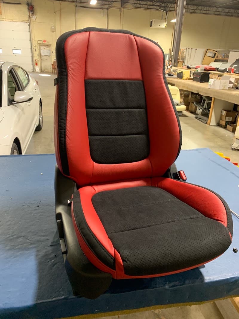Red and black leather car seat on a blue workbench at Mobile Car Pro Norwood in Norwood, Massachusetts