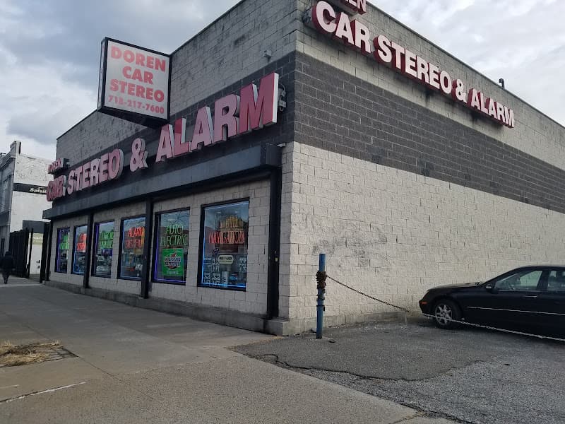 Storefront with red signs and posters in its front windows at Doren Car Stereo & Alarm in Queens Village, New York