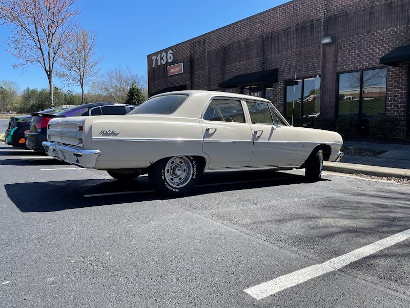 Cream classic sedan with Malibu badge beside brick building at Tunes Car Stereo Concord in Concord, North Carolina