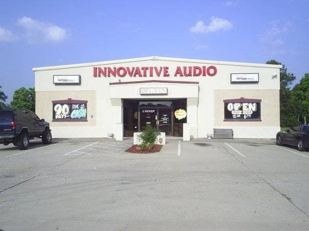Storefront with red sign and two parked vehicles in front at Innovative Audio in Denham Springs, Louisiana