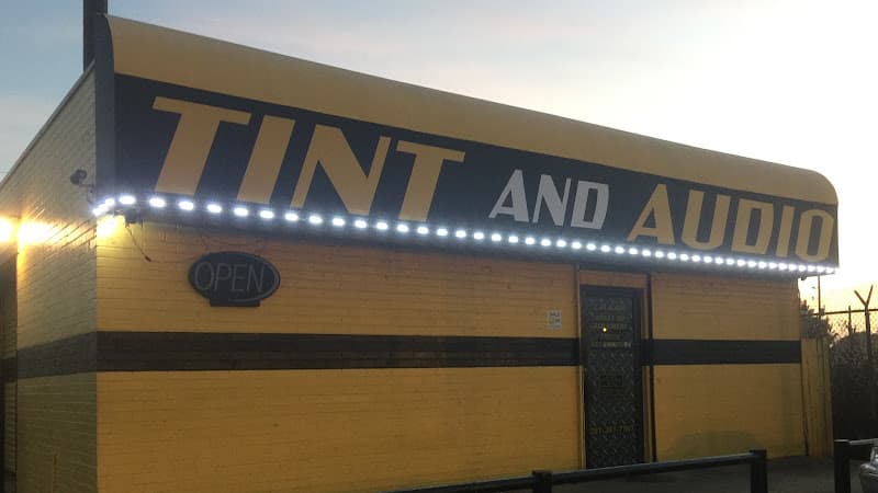 Yellow storefront with TINT AND AUDIO sign, lit up at Hyper Tint & Audio in Katy, Texas