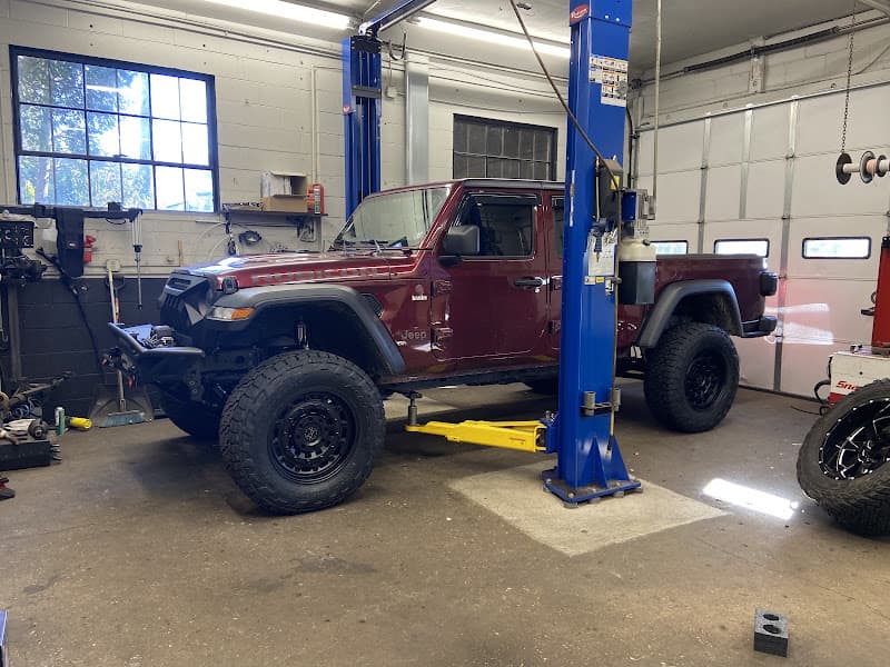 Red Jeep pickup on a two-post lift in a service bay at Automotive Elegance in Toms River, New Jersey