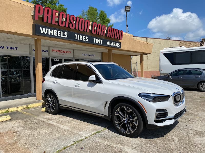 White SUV parked outside storefront with red sign at Precision Car Audio & Truck Accessories in Terrytown, Louisiana