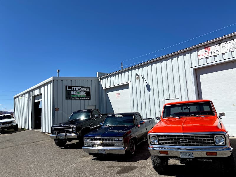 Three pickup trucks parked in front of a metal building at Konnected Auto Restylin' in Grand Junction, Colorado