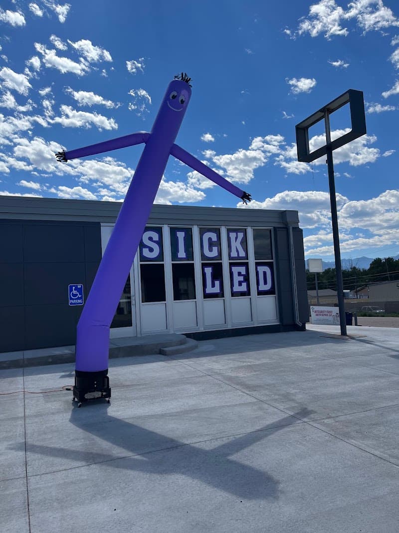 Purple inflatable air dancer outside a shop building at Sick L E D Car Stereo in Colorado Springs, Colorado