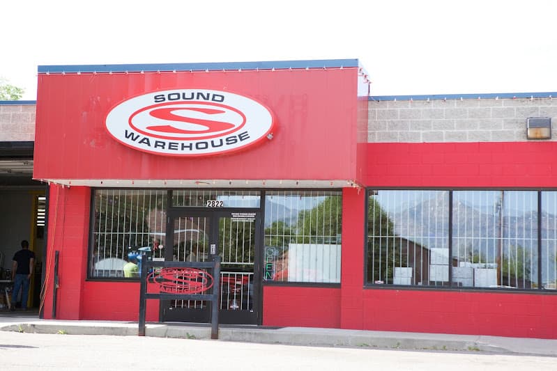 Red storefront with oval logo sign above the entrance at Sound Warehouse in Ogden, Utah