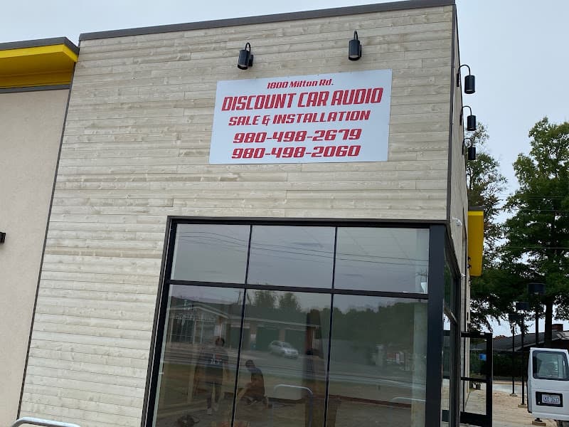 Storefront with white sign and red lettering on wood-look siding at DISCOUNT CAR AUDIO in Charlotte, North Carolina
