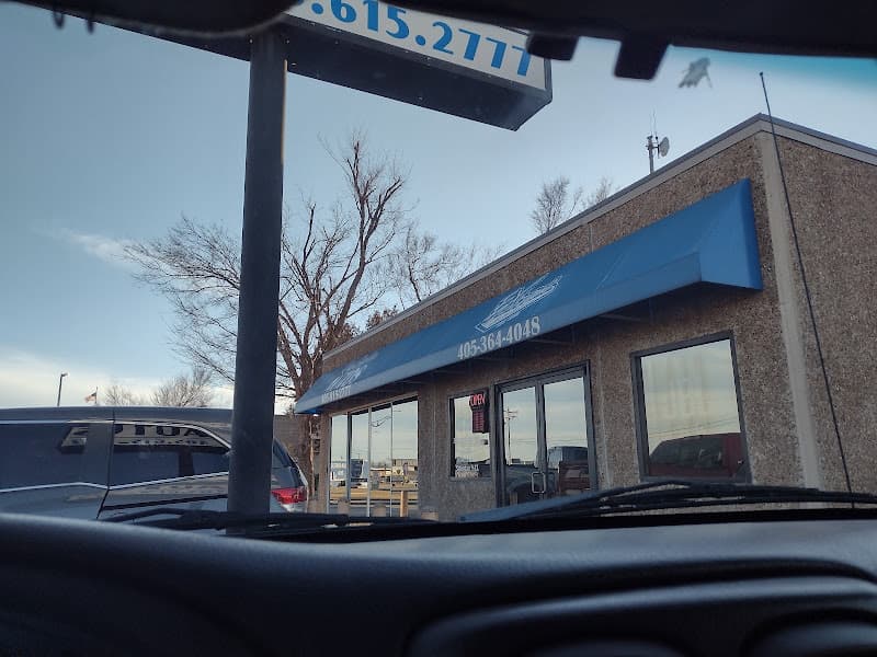 Textured tan storefront with blue awning and glass doors at Extreme Auto Options in Norman, Oklahoma