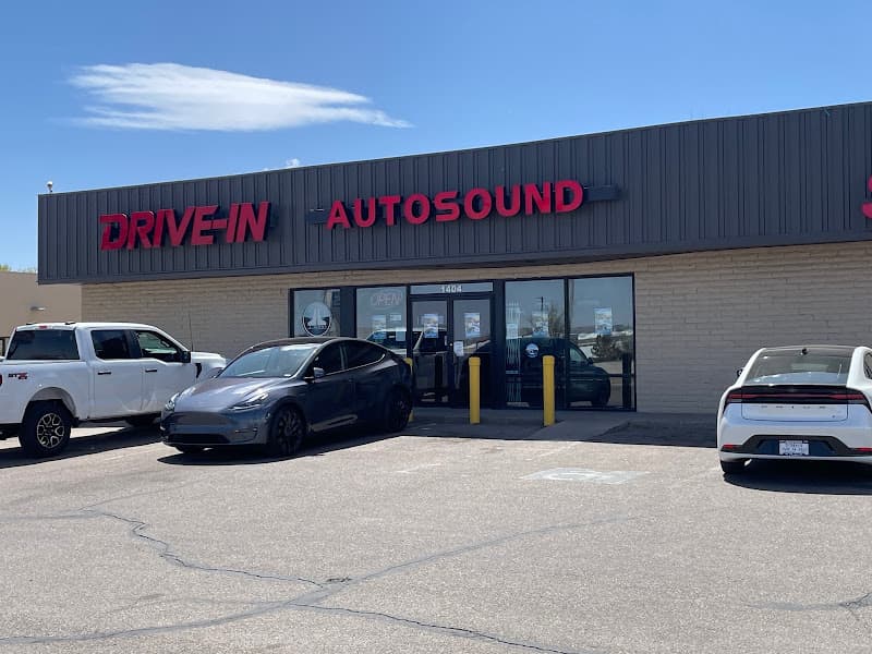 Storefront with red signage and cars parked out front at Drive-In Autosound & Window Tint in Pueblo, Colorado