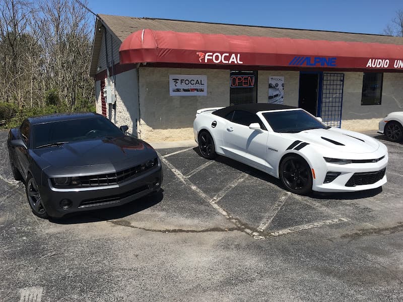 Two sports coupes parked outside storefront with Focal and Alpine signs at Audio Underground in Johnson City, Tennessee