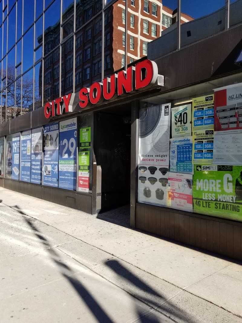Storefront with red sign and phone plan posters in windows at City Sound Electronics in Bridgeport, Connecticut