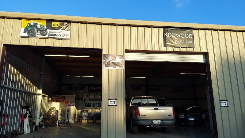 Metal garage with two open bays and a Kenwood Excelon banner at EG Caraudio in Houston, Texas