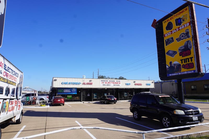Storefront with car stereo and alarm signs and a parked SUV at A-1 Electronics & Car Stereo in Stafford, Texas