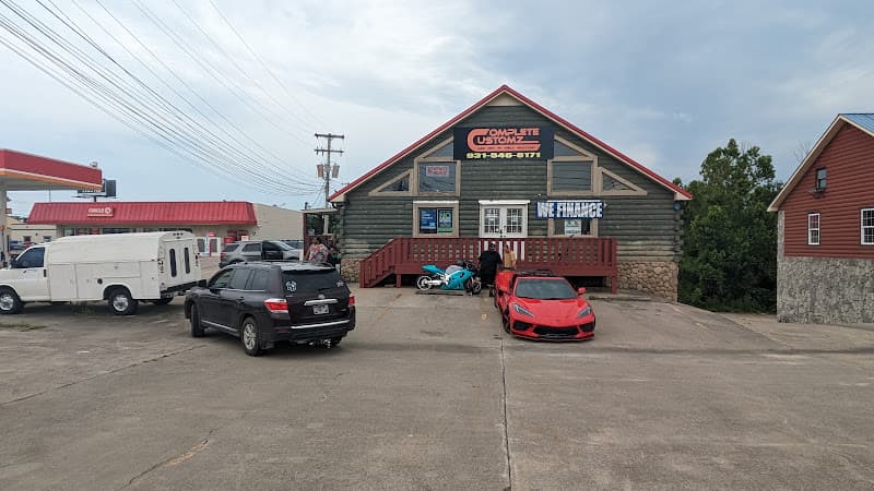 Log-style shop front with red sign and cars parked out front at Complete Customz in Clarksville, Tennessee