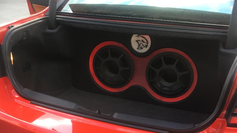 Red car trunk with two subwoofers in red-trimmed box at Automotive Excellence in Buchanan, New York