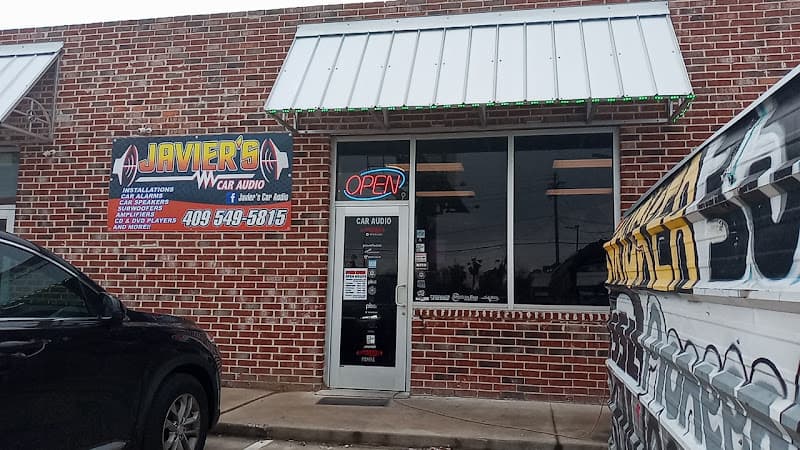 Brick storefront with metal awning and open sign at Javier's Car Audio in Groves, Texas