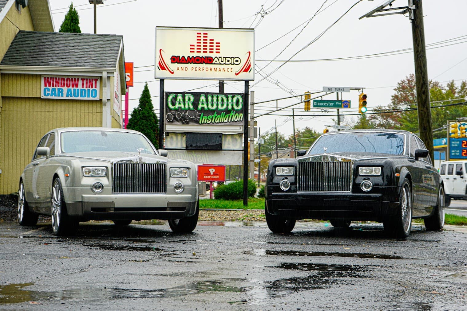 Two silver and black sedans with chrome grilles parked in a wet lot at Diamond Audio & Performance in Lawnside, New Jersey