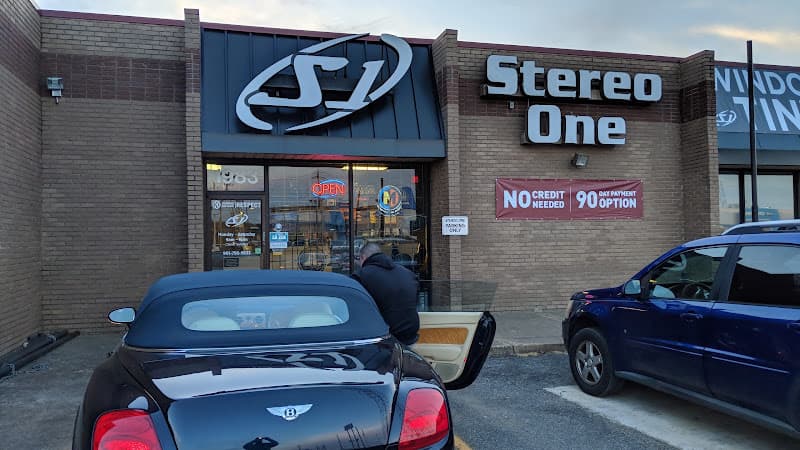 Brick storefront with a logo sign and a black convertible outside at Stereo One Of Covington Pike in Memphis, Tennessee