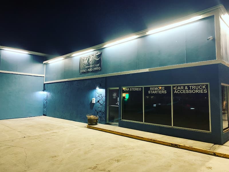 Blue storefront after dark with car stereo window signs at 406 Custom Auto & Sound in Havre, Montana