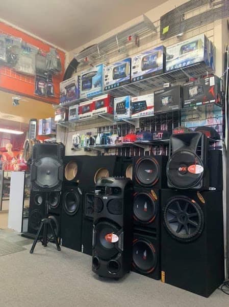Tall black floor speaker on a tripod stand beside stacked speaker boxes at Accesorios Ibanez in Reno, Nevada