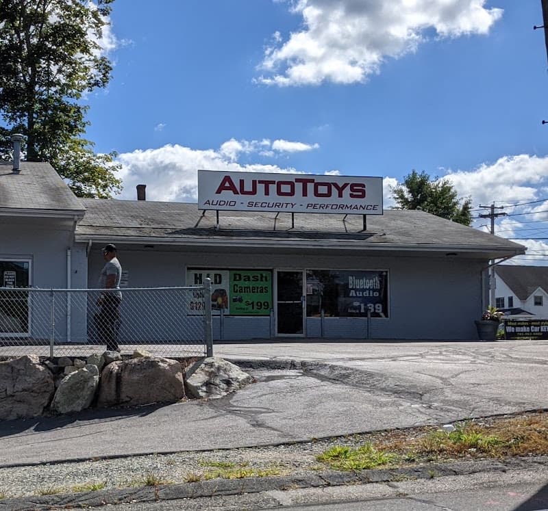 Gray storefront with roof sign and window ads for dash cams and audio at AutoToys in Randolph, Massachusetts