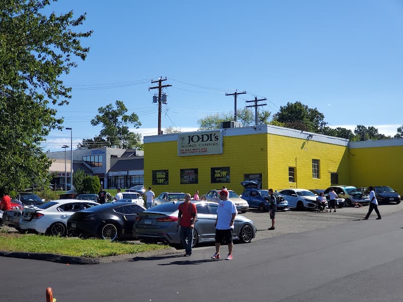 Yellow brick storefront with parked cars and people outside at Jo-Di's Sound Center of Orange in Orange, Connecticut