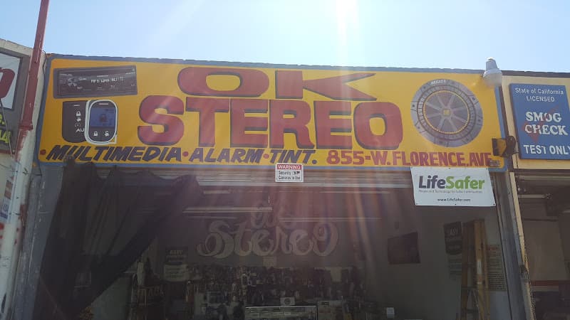 Yellow storefront sign with red lettering and a car stereo graphic at Okay Stereo in Los Angeles, California