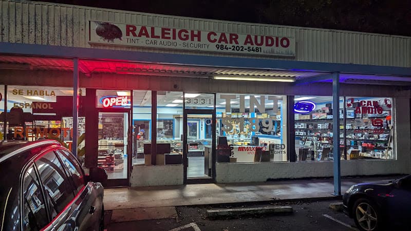 Lit storefront after dark with TINT and CAR AUDIO signs at Mr. Stereo in Raleigh, North Carolina