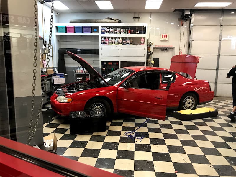 Red coupe with open hood and door in a service bay at Car Toys in Colorado Springs, Colorado