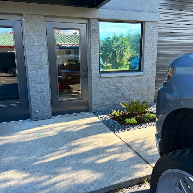 Building entrance with gray doors and a blue vehicle at Connections Car Audio and Electronics in Gainesville, Florida
