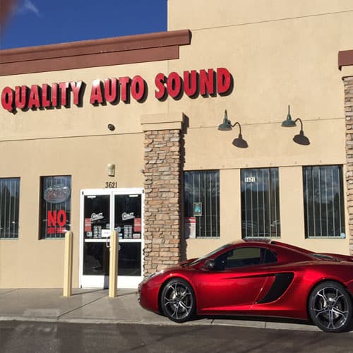 Storefront with red sign and red sports car parked outside at Quality Auto Sound in Greeley, Colorado
