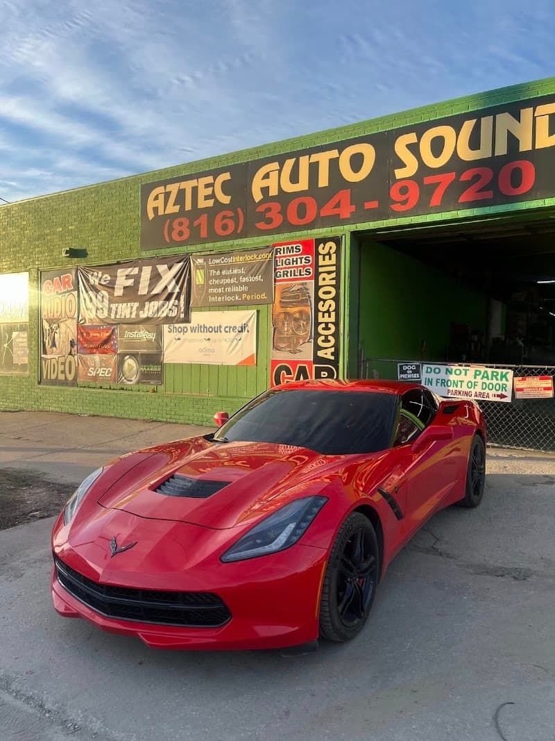 Red sports coupe parked in front of storefront at Aztec Auto Sound in Kansas City, Missouri