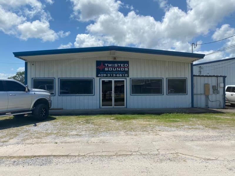 Metal storefront with blue trim and pickup truck parked outside at Twisted Sounds in Orange, Texas