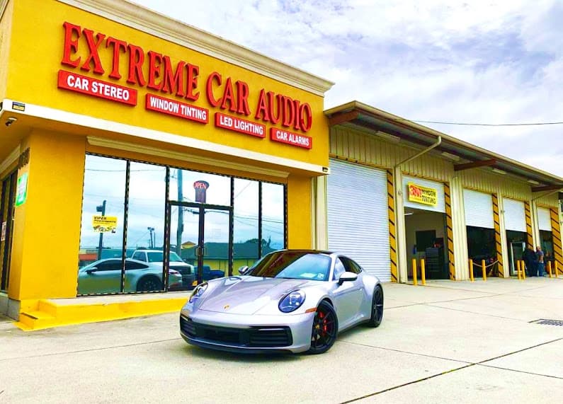 Silver sports car parked in front of a yellow storefront at Extreme Car Audio LLC in Marrero, Louisiana