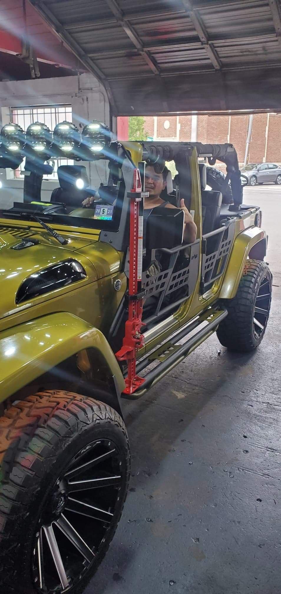 Olive green open-top SUV with roof lights, man giving thumbs up at P&P CUSTOMS in Paterson, New Jersey